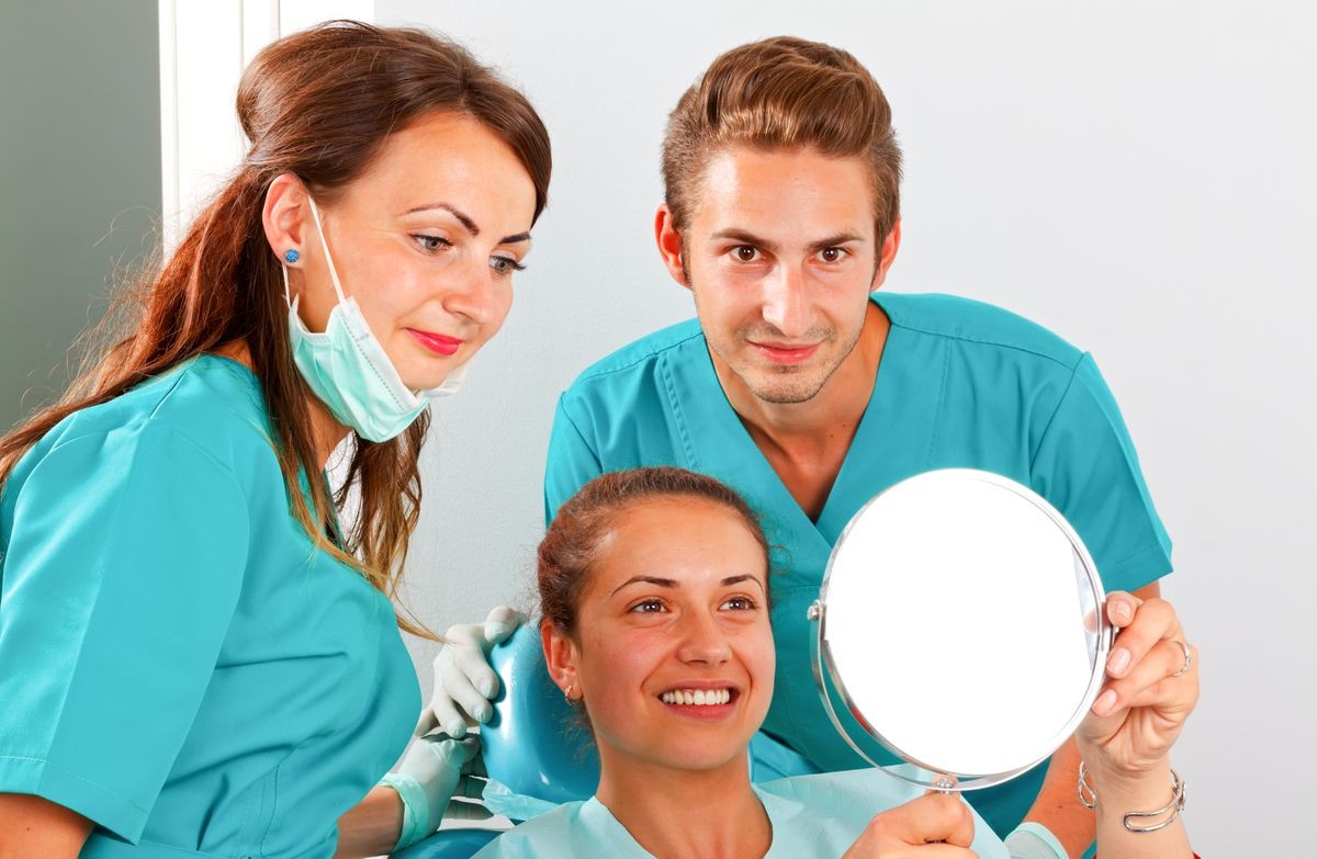Medical dental team and patient checking the treatment result in a mirror